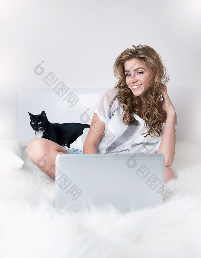 毛毯上玩电脑的女人和小猫