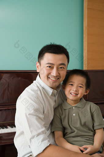 暗色调钢琴旁的父子摄影图