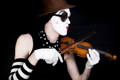 暗色调拉小提琴的小丑摄影图