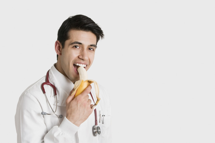 简约吃香蕉的医生摄影图