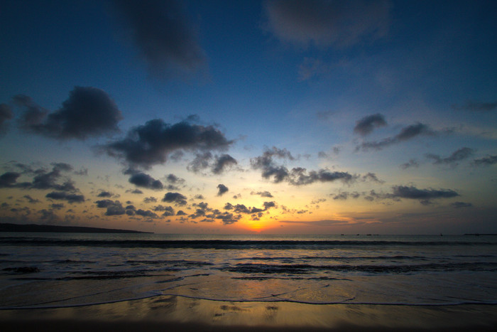 暗色调夕阳下平静的海滩摄影图