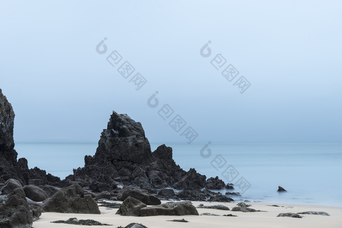 海滩边的礁石沙滩摄影图