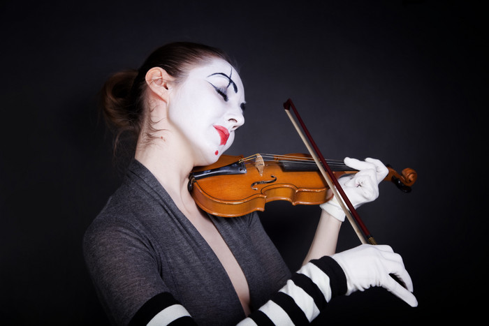 黑色风拉小提琴的小丑摄影图