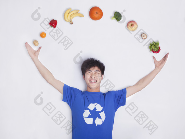 年轻的男子休闲的着装躺着环保蔬菜水果