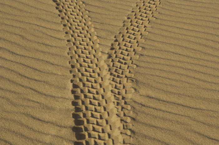 暗色调沙漠中的轮胎印摄影图