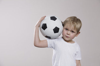 深色调玩足球的孩子摄影图