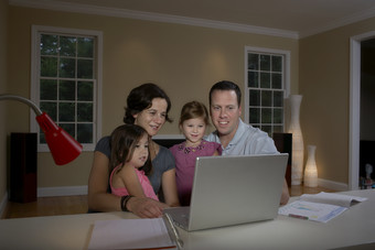 暗色调看电脑的一家人摄影图