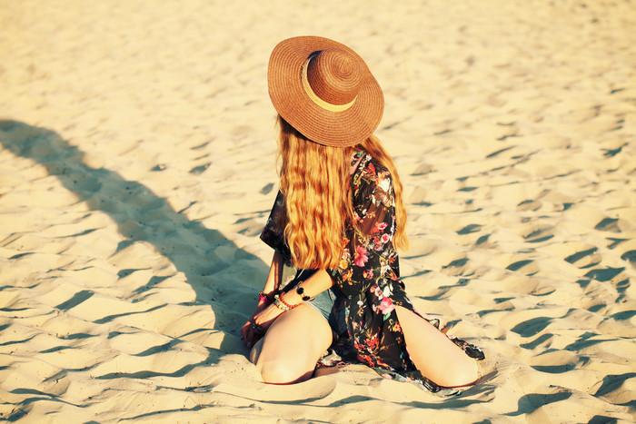 跪在沙子上的戴帽子女人