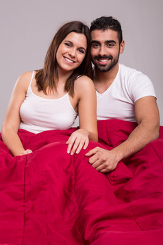 床上盖棉被的夫妻笑脸