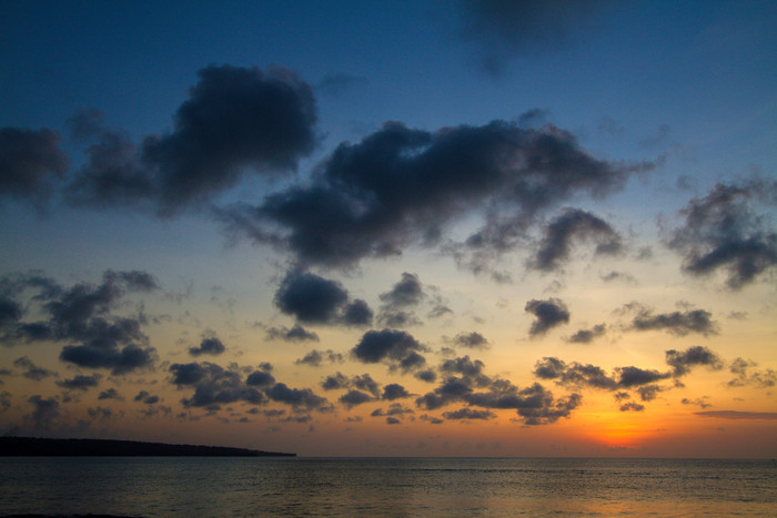 深色调夕阳下的海平面摄影图