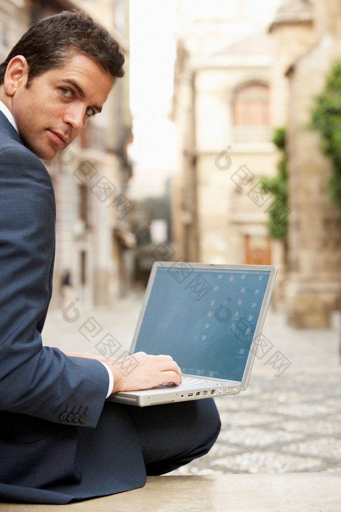 户外男人坐在地上打电脑