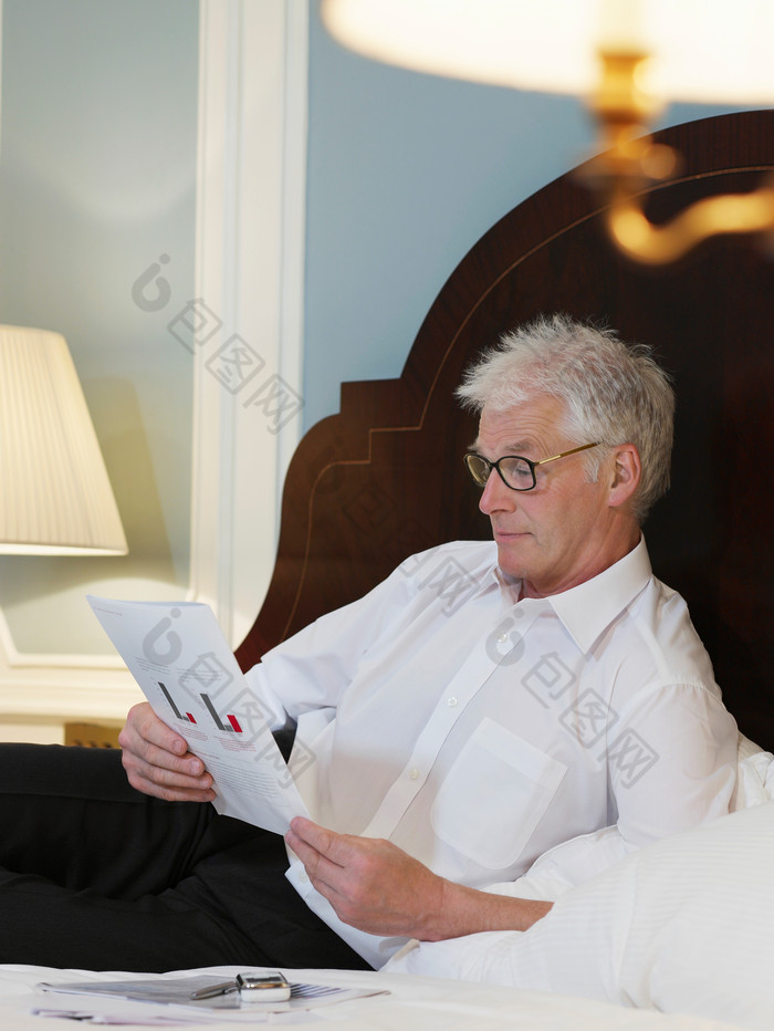 中年商务男士躺床上看书