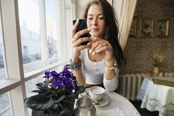 女人坐在餐厅<strong>喝咖啡</strong>看手机