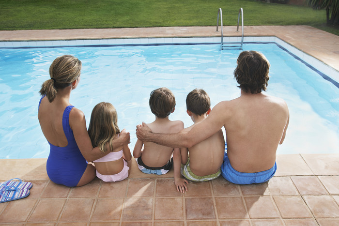 坐泳池边的一家人