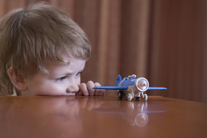 桌子上玩飞机玩具的小男孩