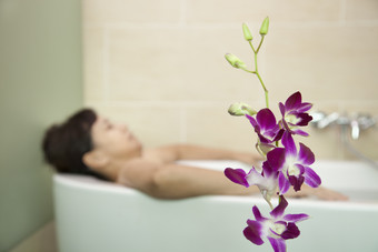 女人躺着浴室浴缸舒服的洗澡沐浴蝴蝶兰花朵