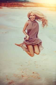 海滩跳跃的金发女人