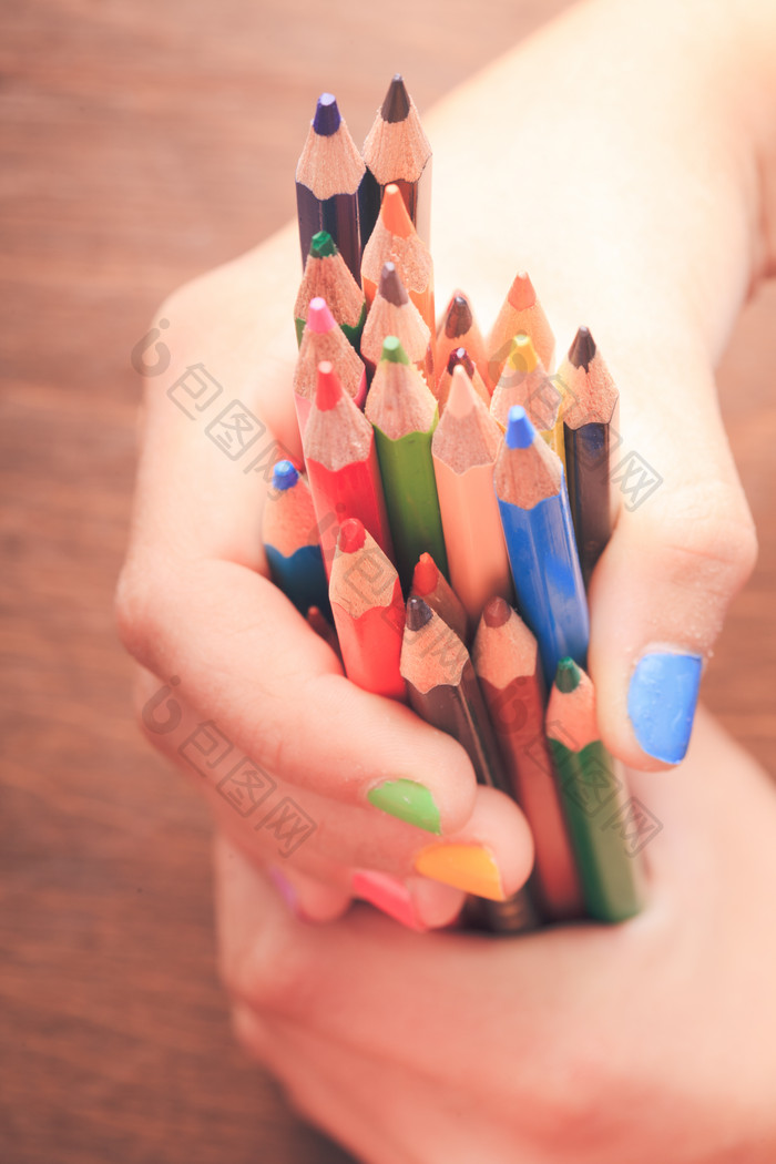 双手抓着一把彩色铅笔