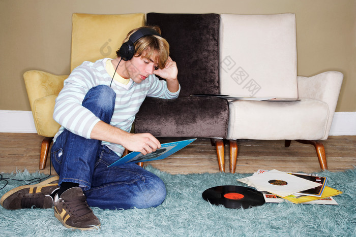 坐在地毯上听音乐的男生