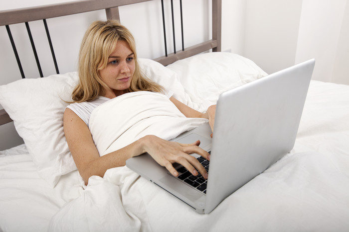 简约床上用电脑的女人摄影图