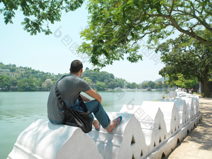 深色调水边坐着的男人摄影图