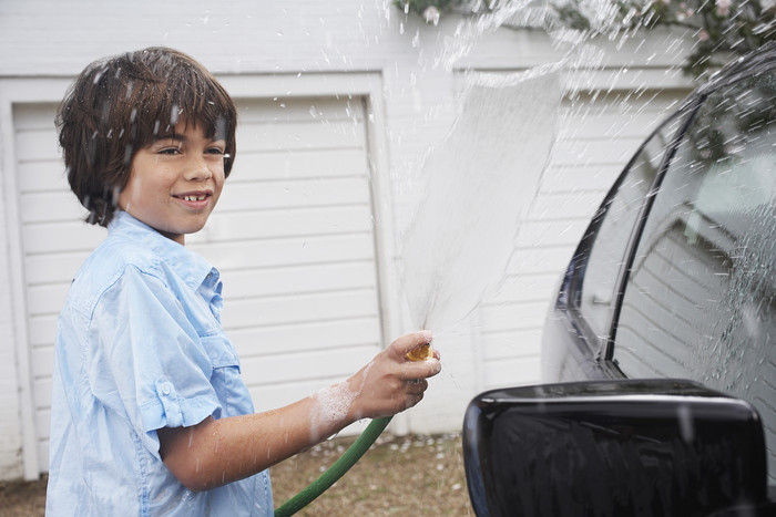 拿水管洗车的小男孩
