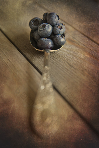 暗色汤匙中的蓝莓摄影图