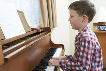 简约弹钢琴的小男孩摄影图