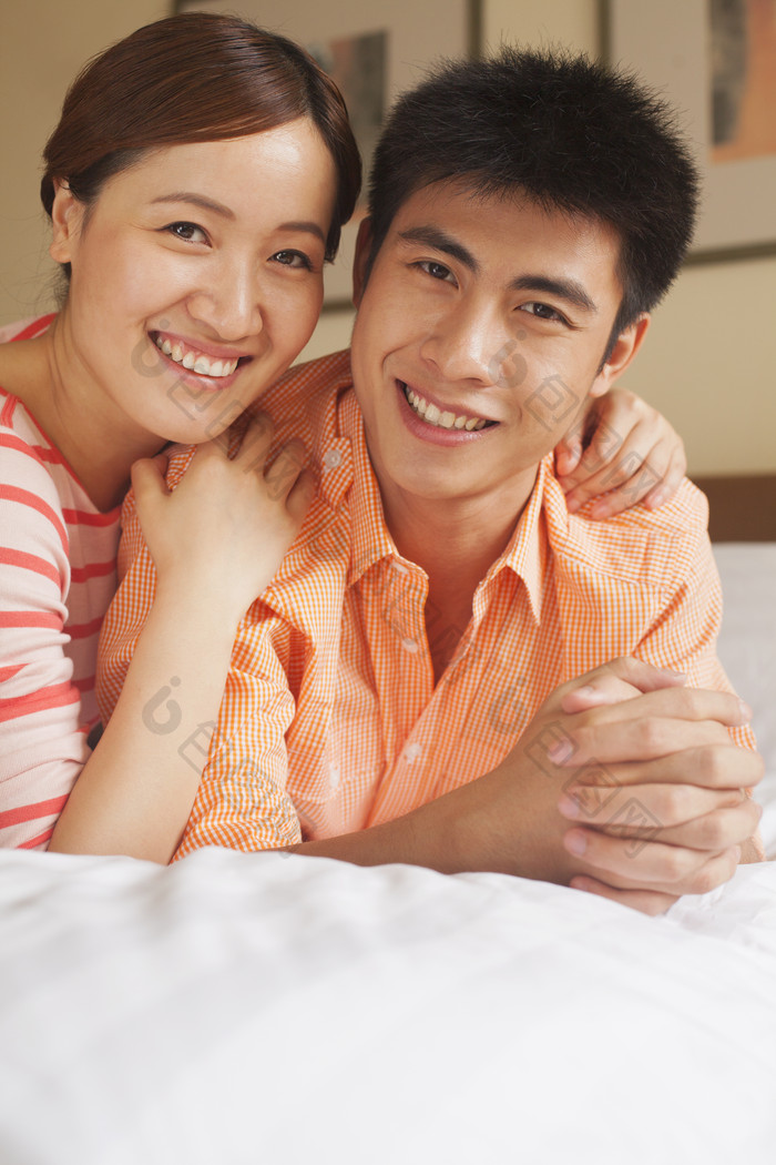 夫妻男人女人床上躺着微笑洁白的牙齿摄影图