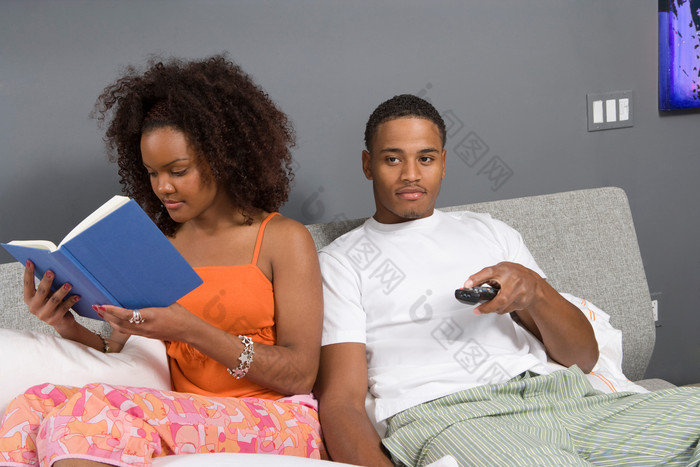 床上看电视和看书的夫妻