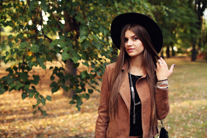 穿棕色夹克女孩站在树下