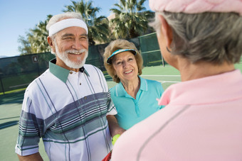 深色调跟好友打网球的夫妻摄影图