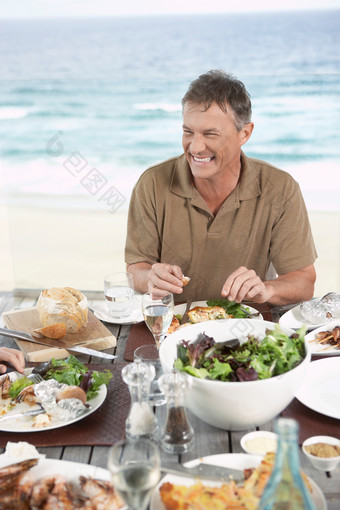 海边吃饭的男人摄影图