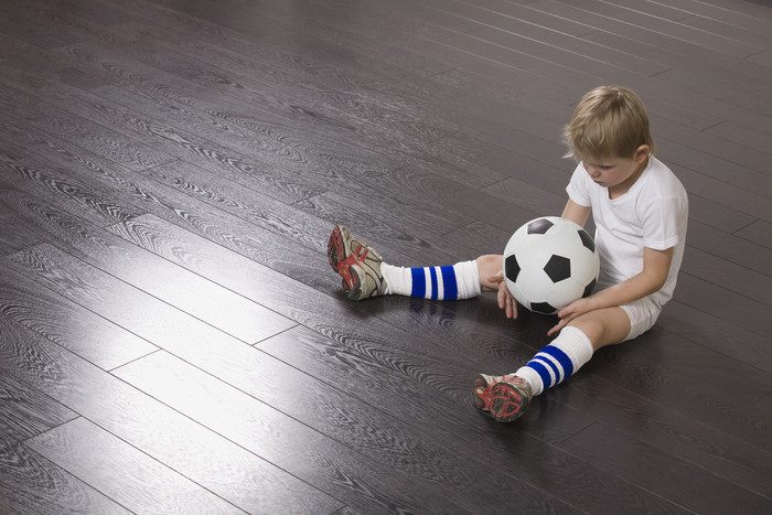 男童沮丧的坐在地板上抱着足球