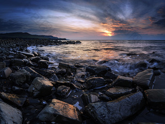 傍晚海岸边的岩石摄影图