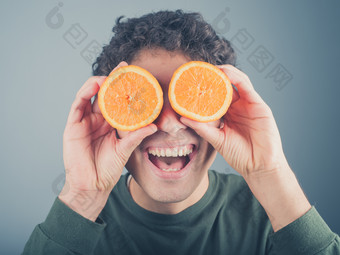 男人拿着两个半橙子在眼前