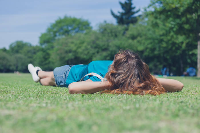绿色躺在草地上的女孩摄影图