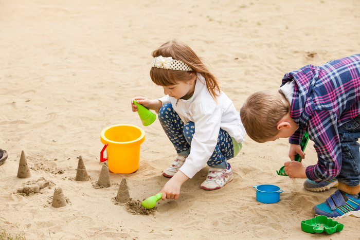 深色调玩沙子的儿童摄影图