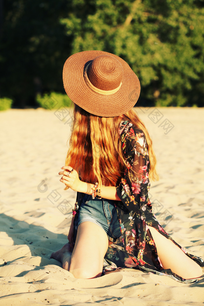 跪沙滩上戴帽子的美女
