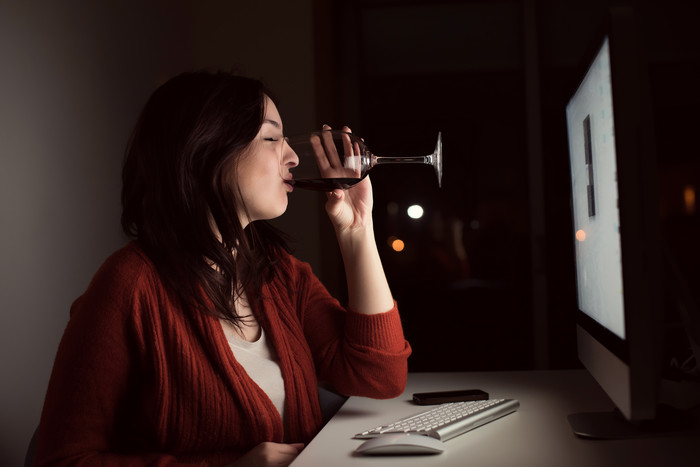 暗色调电脑前喝酒的女人摄影图