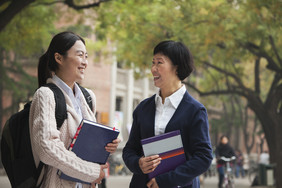 女人成熟的老师学生抱着书学校户外片