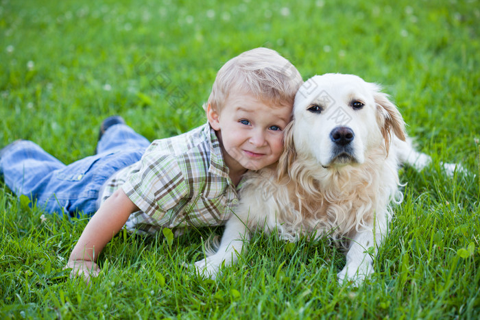 趴在草地上的小男孩和狗