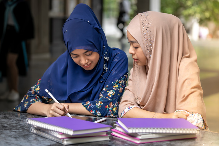 穆斯林教育训导两个戴着头巾的女孩讨论学校