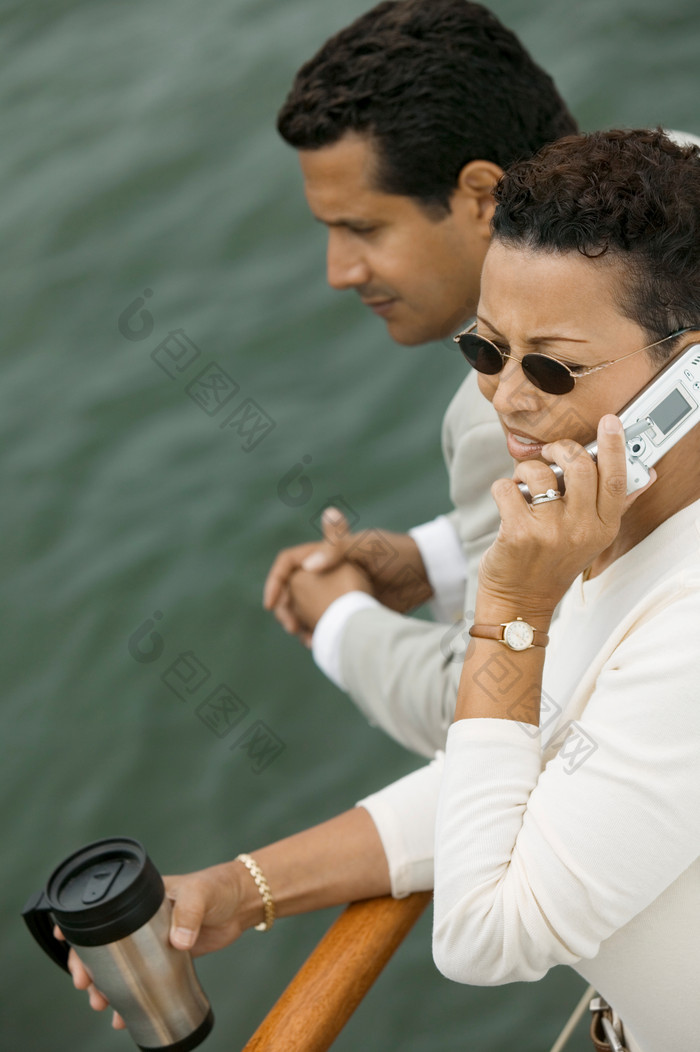 深色调在船上打电话的夫妻摄影图