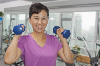 成熟的女人妇女举重举哑铃运动锻炼健身摄影