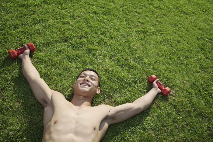 躺着草地上男子赤裸健壮的健身举着哑铃双手