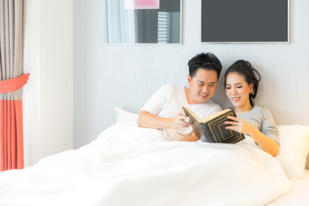 床上看书的夫妻摄影图