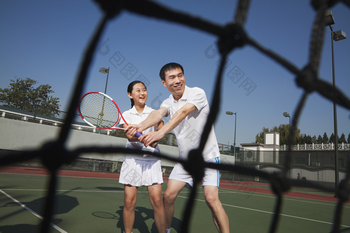 球网后打网球的父女