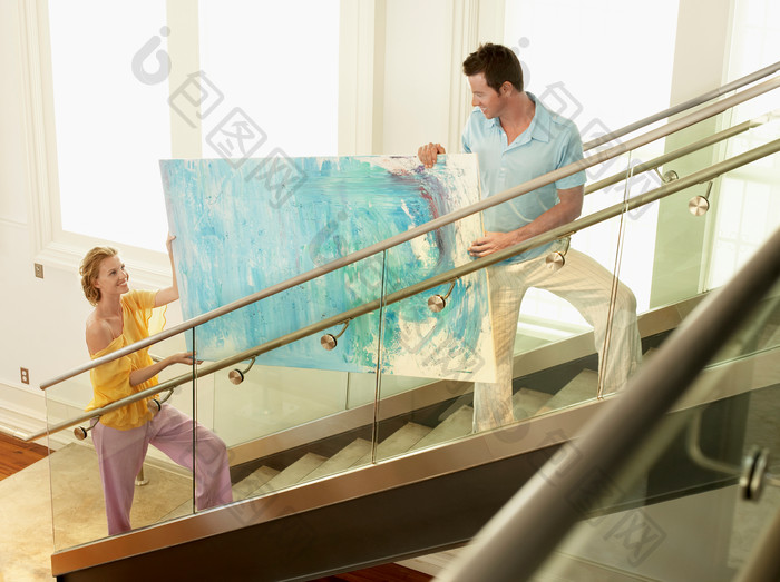 夫妻拿着一幅画上楼梯
