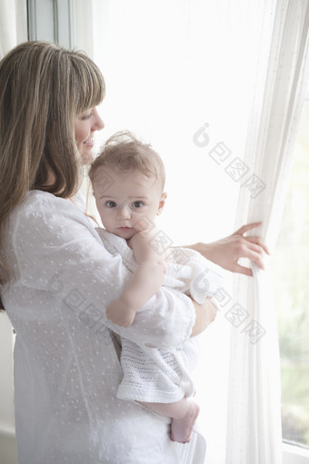 母亲抱着宝宝掀开窗帘